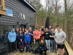 a group of students and staff stand in front of the Black Oak at Lost RIver Vacations with trees in the background.
